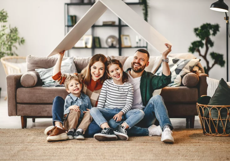 Symbolfoto von 5min.at: Eine glückliche Familie zuhause im Wohnzimmer.