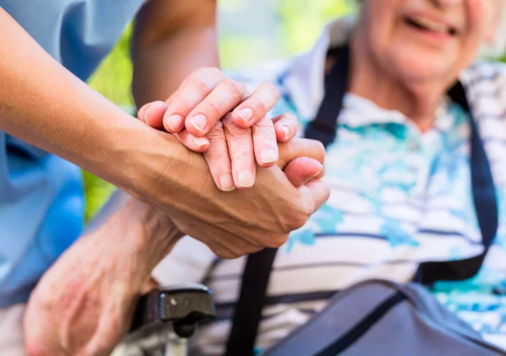 Symbolfoto von 5min.at: Altenpflegerin hält die Hand einer Seniorin.