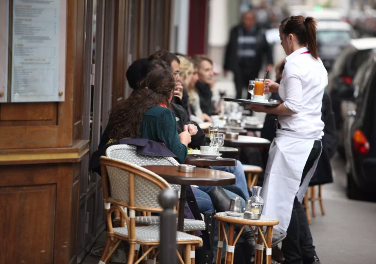 Symbolfoto von 5min.at: Besucher sitzen vor einem Café und werden bedient.