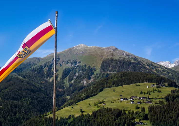 Symbolfoto von 5min.at: Kärnten Flagge vor Bergkulisse im Lesachtal.
