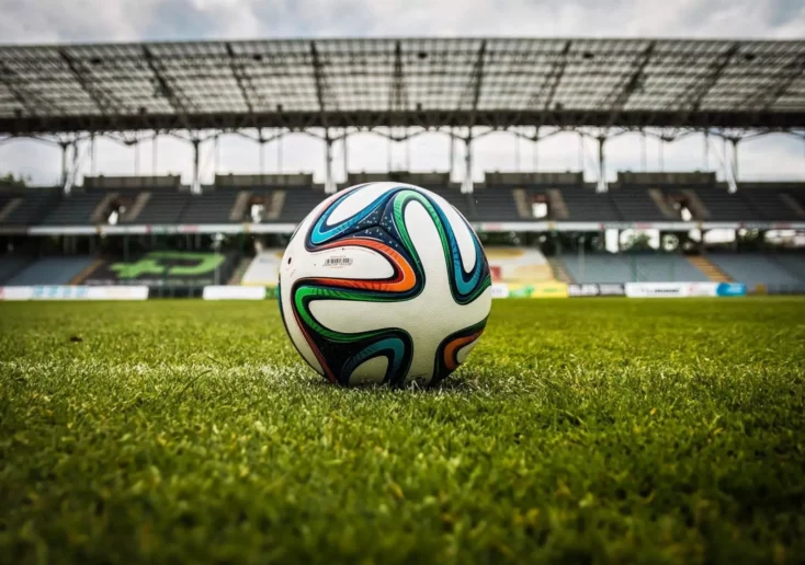 Symbolfoto zu einem Beitrag von 5min.at: Ein Fußball liegt auf dem Rasen in einem Stadion