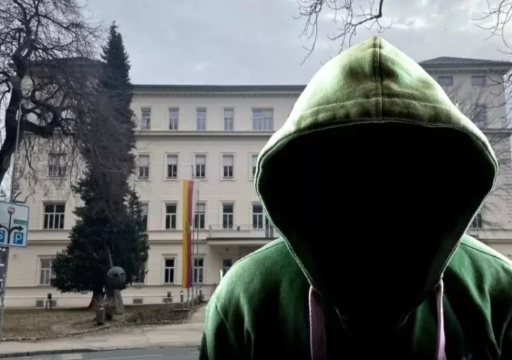 Symbolfoto zu einem Beitrag von 5min.at: Mann mit Kapuze steht vor einem öffentlichen Gebäude
