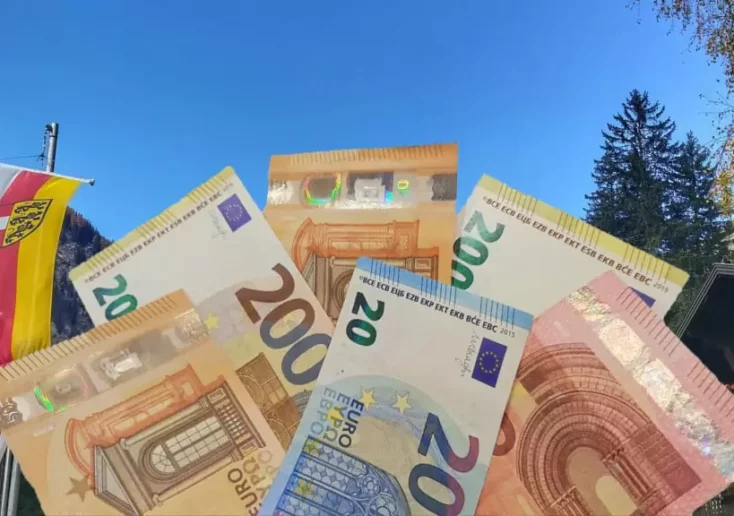 Symbolfoto von 5min.at: Fotomontage von Geld und den Kärntner Alpen mit Wappen.