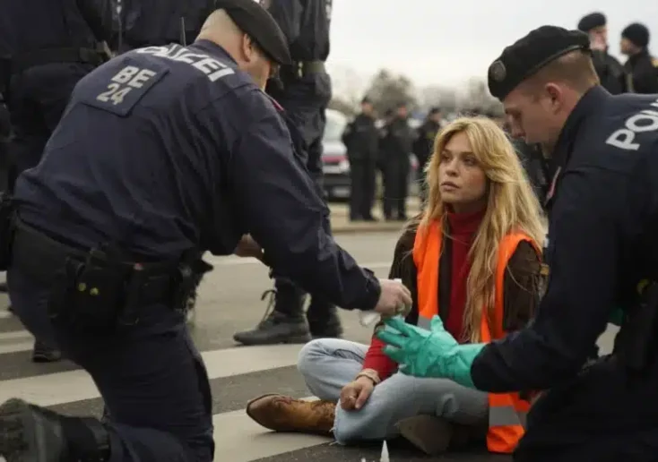 Symbolfoto zu einem Beitrag von 5min.at: Klima-Kleberin Anja Windl beim Protest und mehreren Polizisten