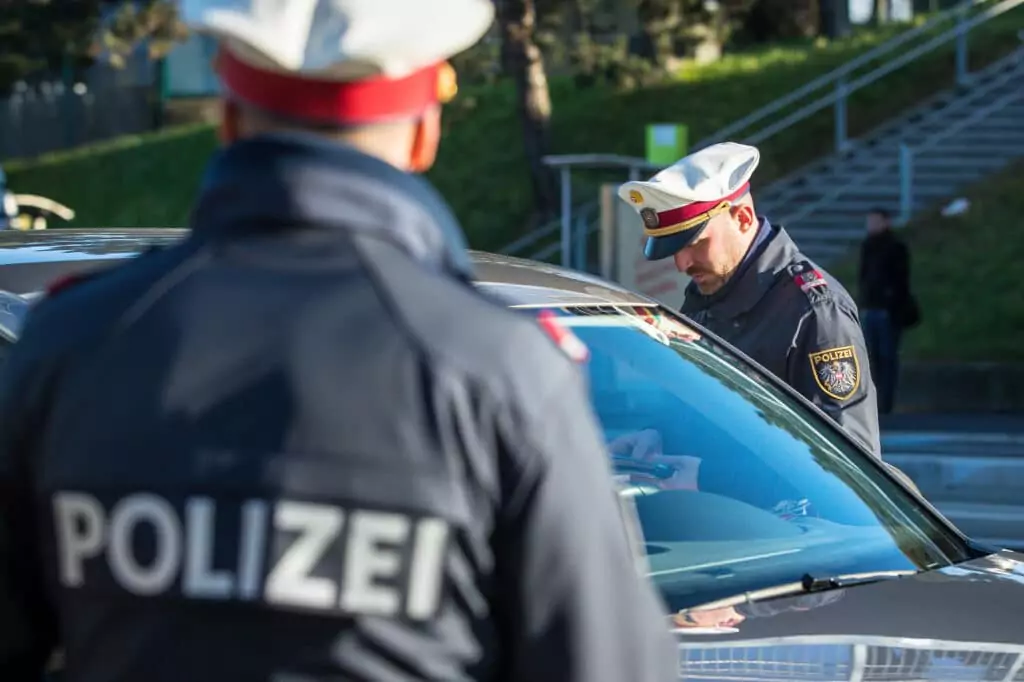 Symbolfoto von 5min.at: Polizisten kontrollieren den Führerschein eines Autofahrers.