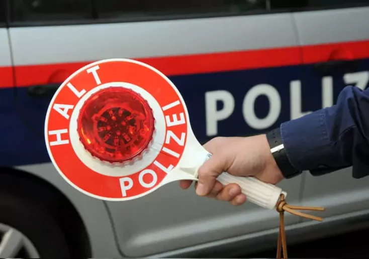 Symbolfoto von 5min.at: Polizist hält ein Halteschild in der Hand.