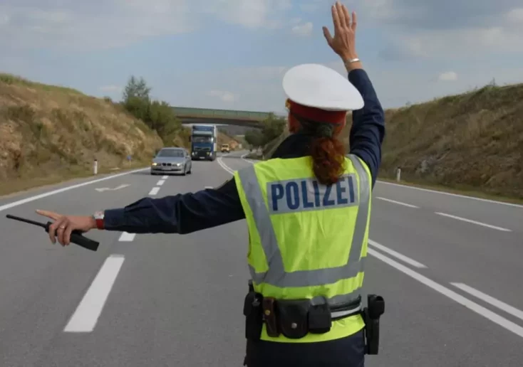 Symbolfoto von 5min.at: Polizistin hält Autos zur Kontrolle auf.