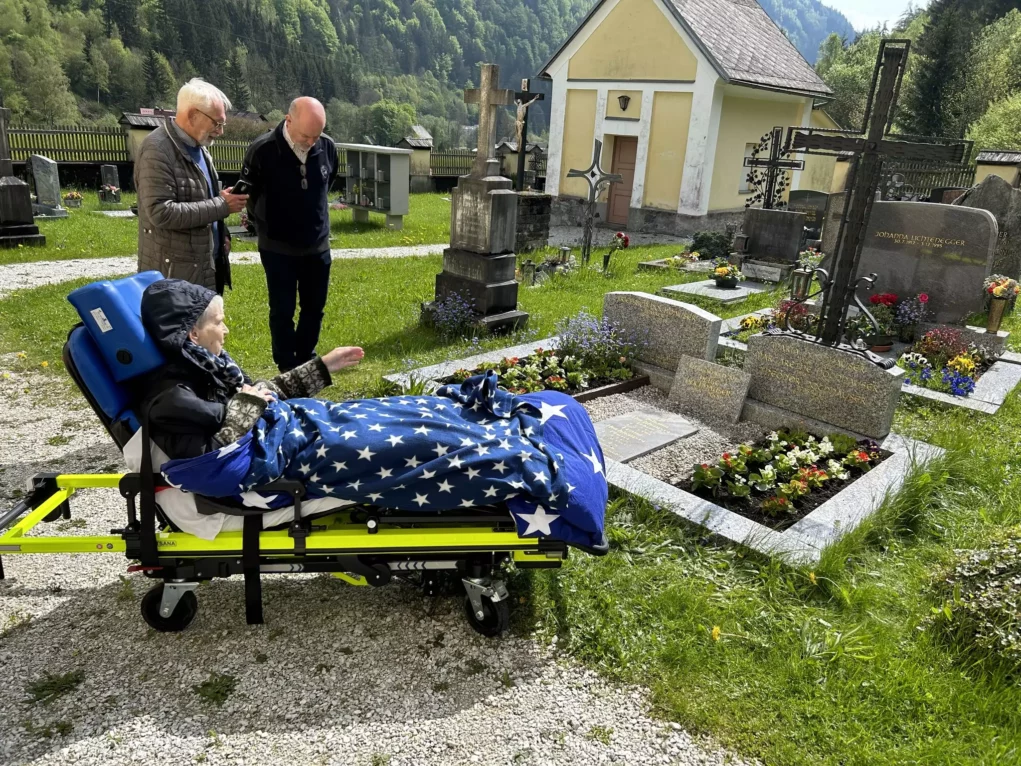 Bild auf 5min.at: Eine schwerkranke Frau gemeinsam mit Mitarbeiter des Vereins Rollende Engel auf einem Friedhof.