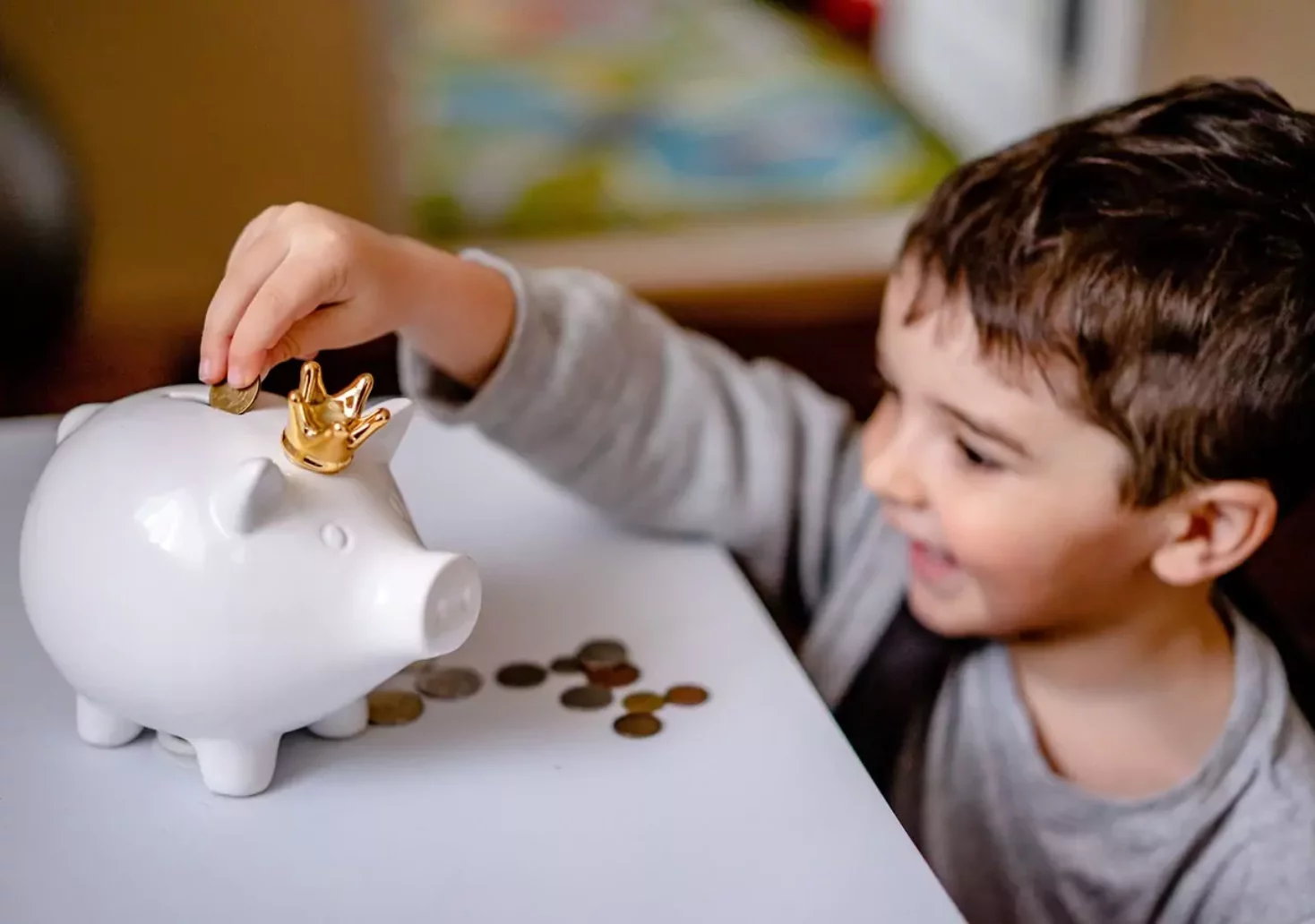 Foto auf 5min.at zeigt ein Kind, welches Geldmünzen in ein Sparschwein gibt.