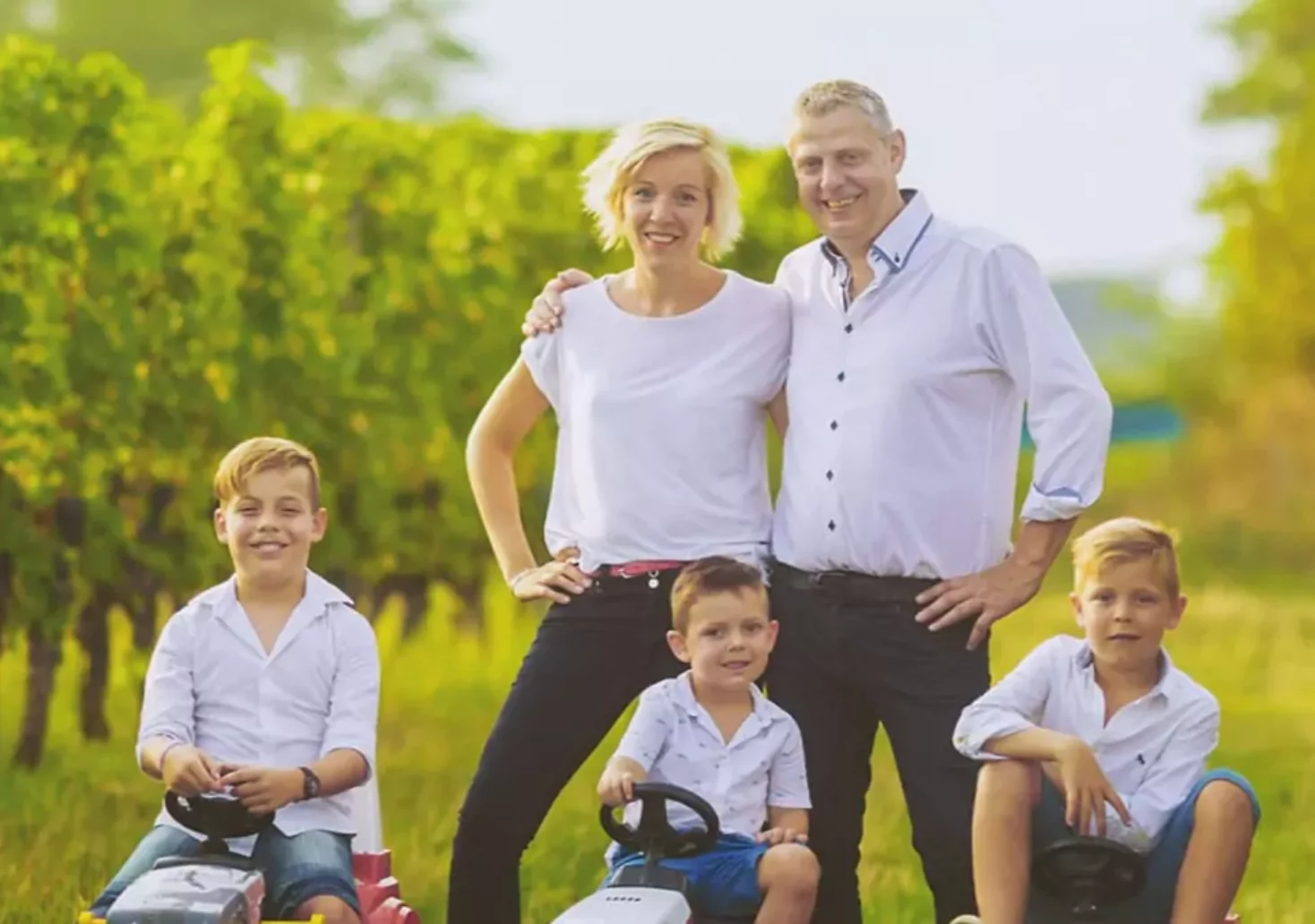 Foto im Beitrag von 5min.at: Glückliche Familie mit drei Kindern steht auf einem Weingut.