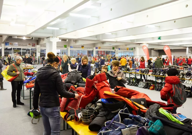 Foto in Beitrag von 5min.at: zu sehen ist die Wintersportbörse der Arbeiterkammer mit vielen Wintersportartikeln und einigen Personen, die sie kaufen wollen.