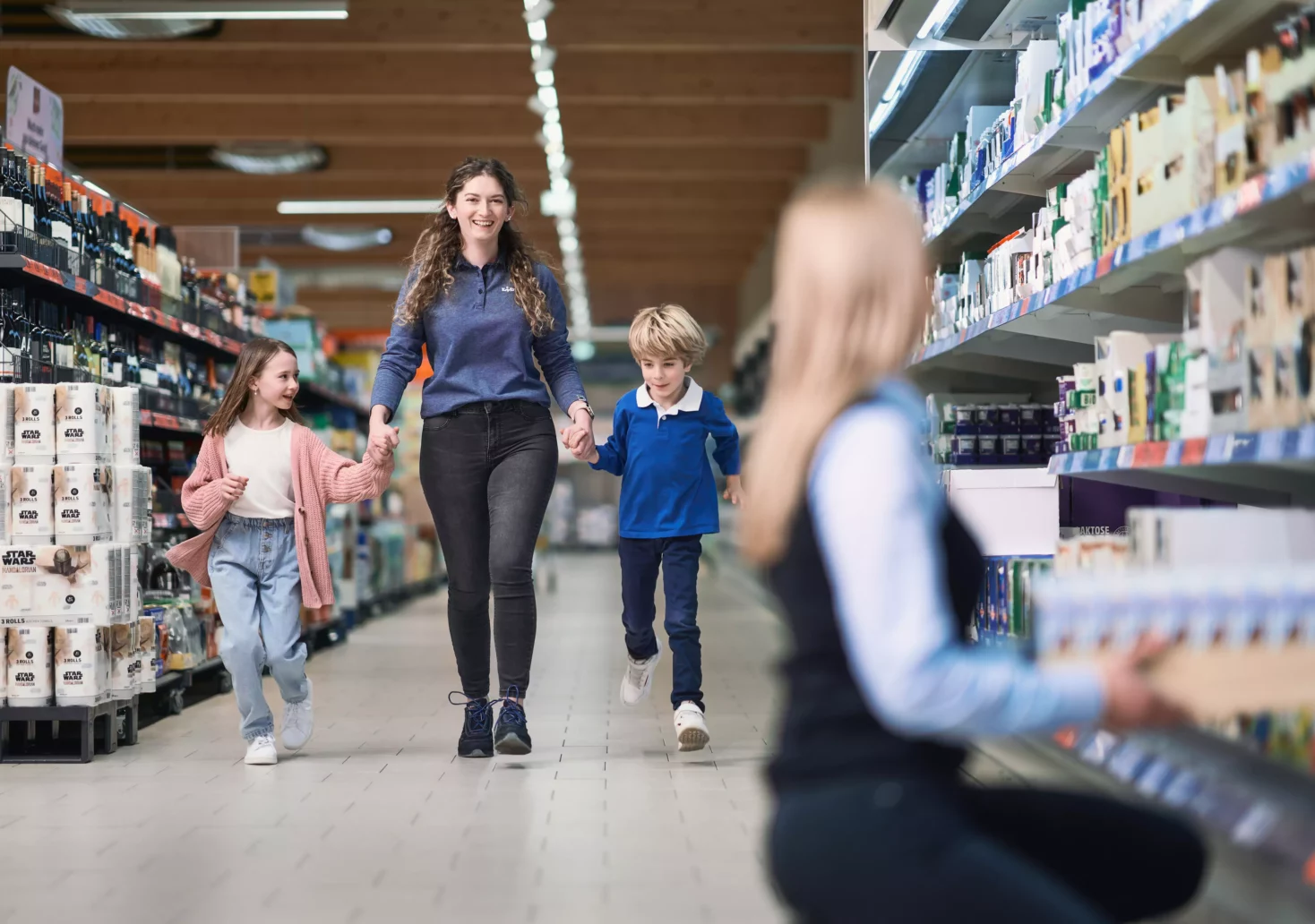 Foto auf 5min.at zeigt eine Lidl-Mitarbeiterin mit zwei Kindern an der Hand durch die Einkaufsgänge gehen.