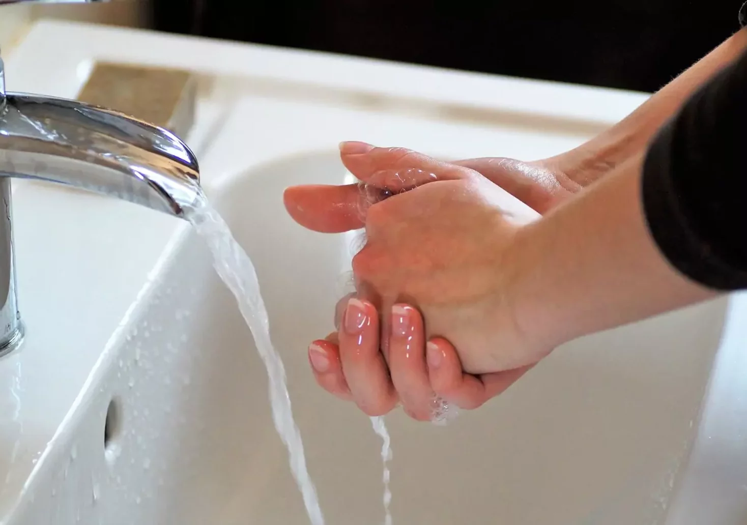 Ein Bild auf 5min.at zeigt eine Frau, die sich die Hände unter einem laufenden Wasserhahn wäscht.