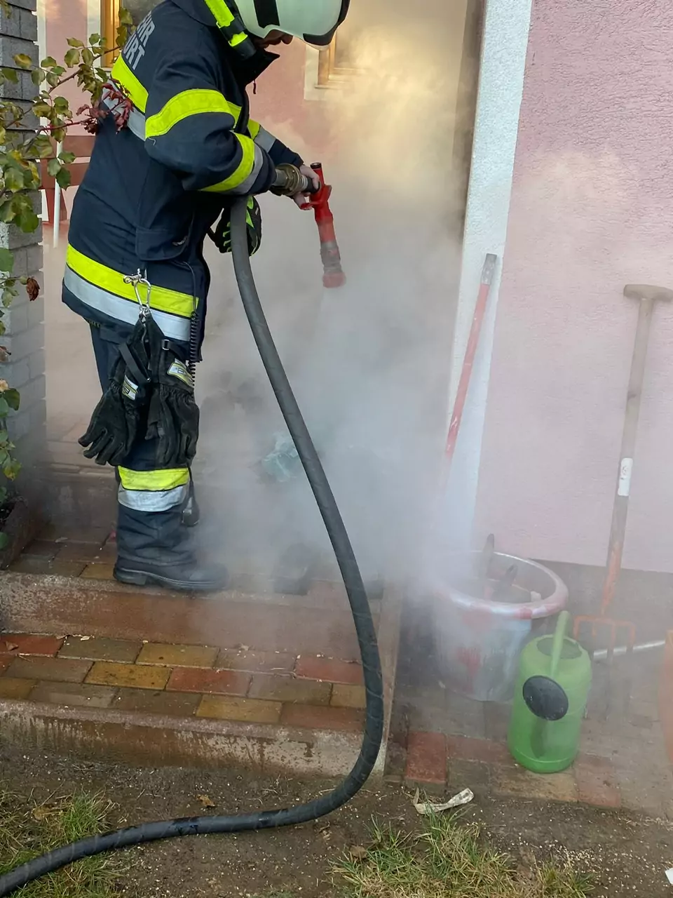 Foto in Beitrag von 5min.at: Zu sehen ist ein Floriani, der geraden den Hausfassadenbrand löscht.