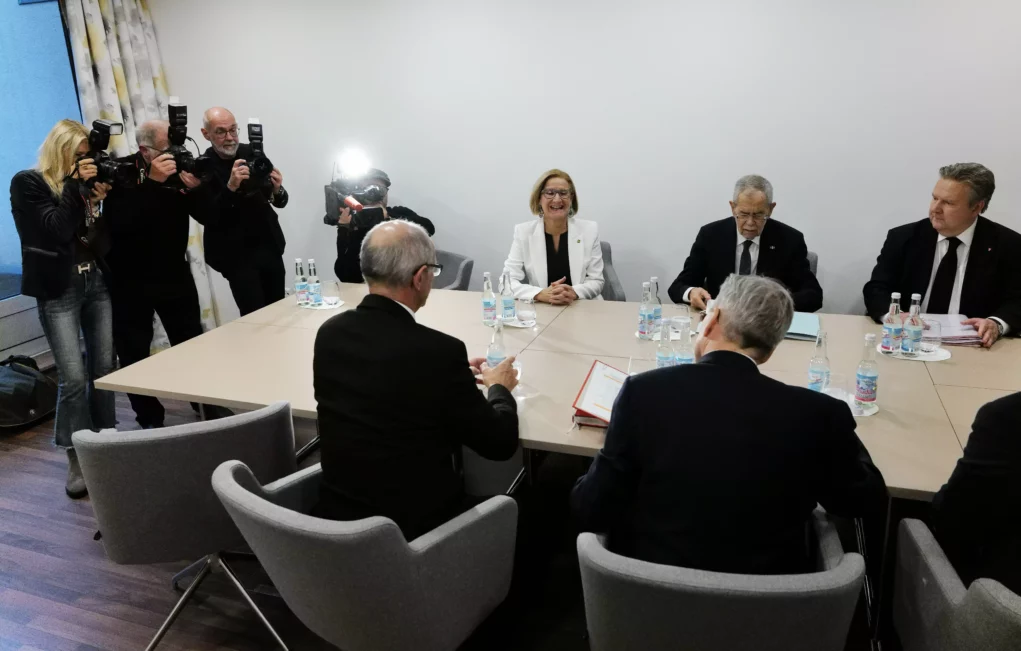 Ein Foto auf 5min.at zeigt Bundespräsident Alexander Van der Bellen im Austausch mit den Landeshauptleuten. Sie alle sitzen an einem Sitzungstisch, Pressefotografen stehen im Hintergrund.
