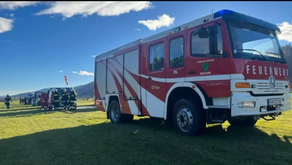 Ein Bild auf 5min.at zeigt ein Feuerwehrauto, dass auf einer Wiese parkt.