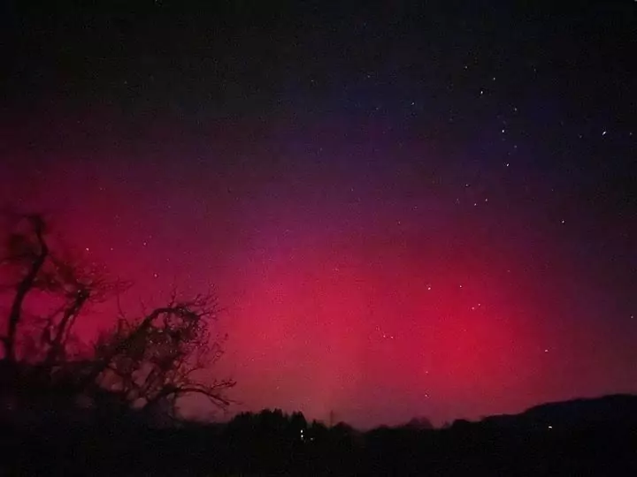 Ein Bild auf 5min.at zeigt pinkfarbene Polarlichter, die am Nachthimmel leuchten.