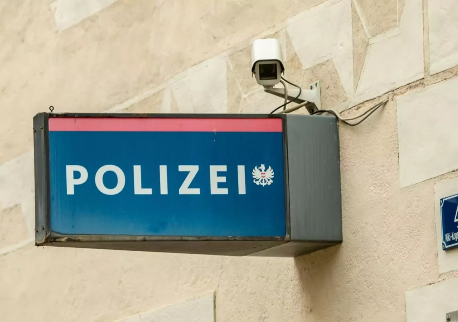 Ein Bild auf 5min.at zeigt ein blaues Schild mit rotem Streifen, auf dem in weißen Buchstaben das Wort Polizei steht.