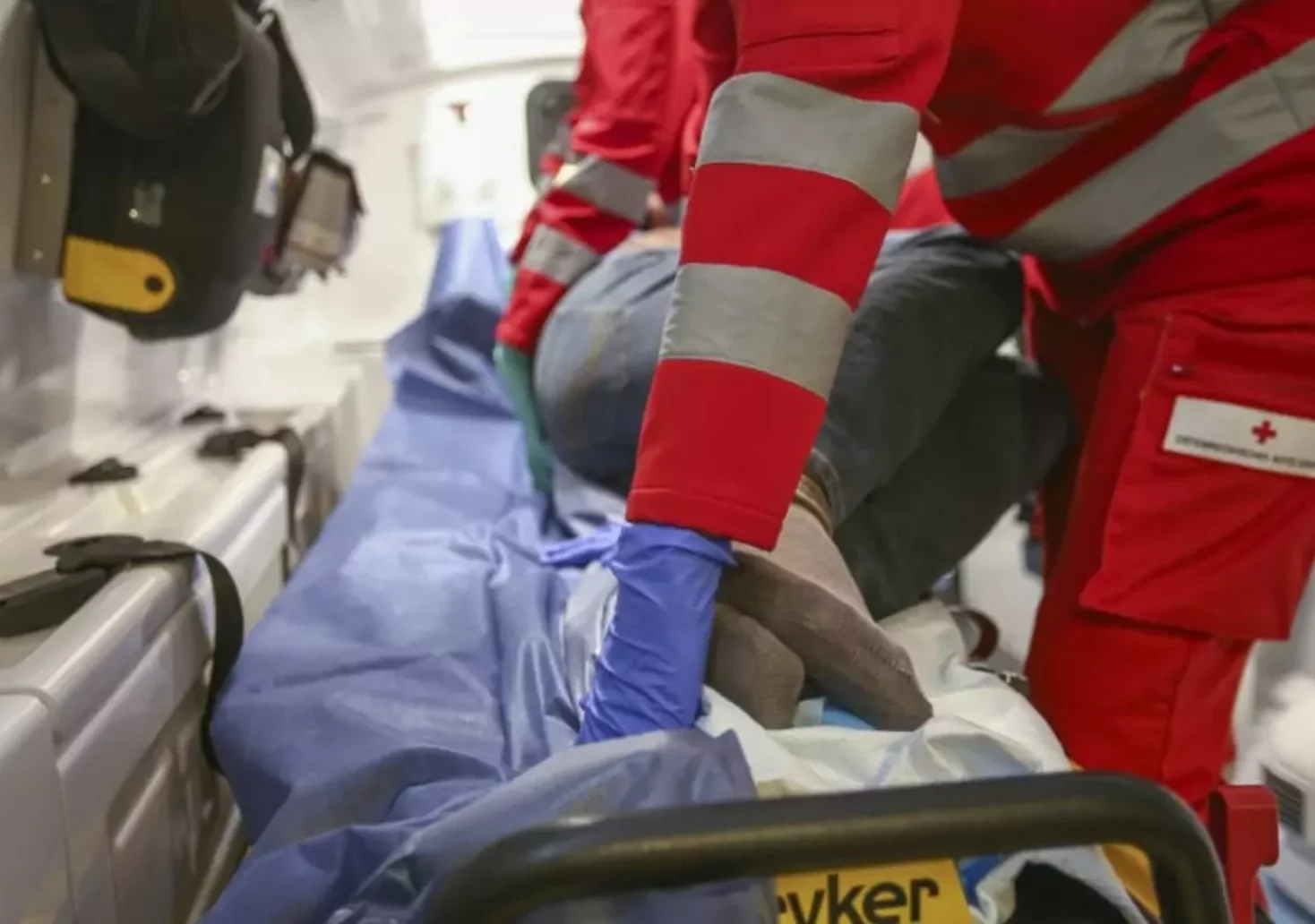Ein Bild auf 5min.at zeigt einen Rettungssanitäter, der eine Verletzte in einem Rettungswagen verarztet. Die Frau befindet sich in einer stabilen Seitenlage.