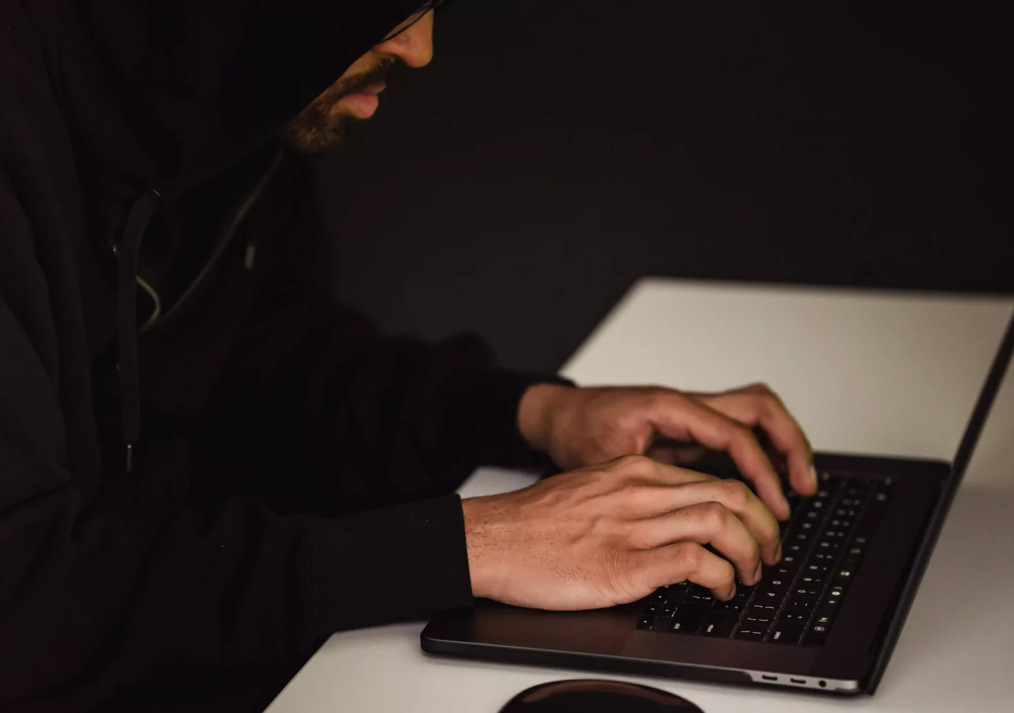 Ein Bild auf 5min.at zeigt einen Mann im dunklen Kapuzenpulli, der vor einem Laptop sitzt und auf der Tastatur tippt.