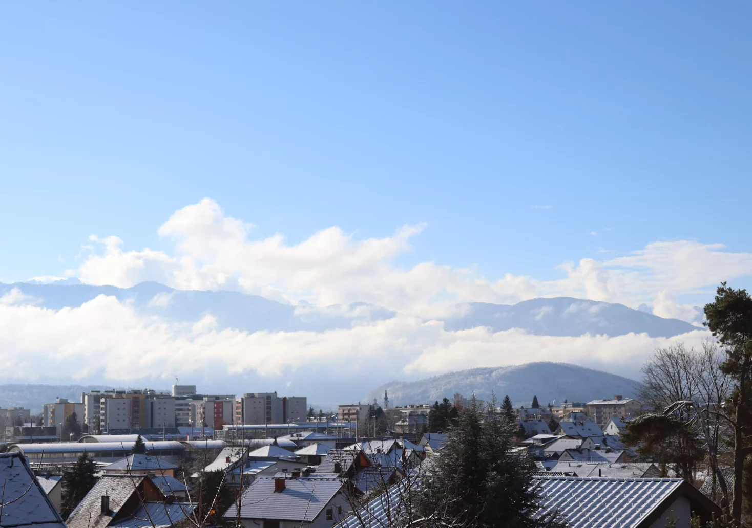 Ein Bild auf 5min.at zeigt das verschneite Villach vor einer Bergkulisse. Der Himmel ist blau.