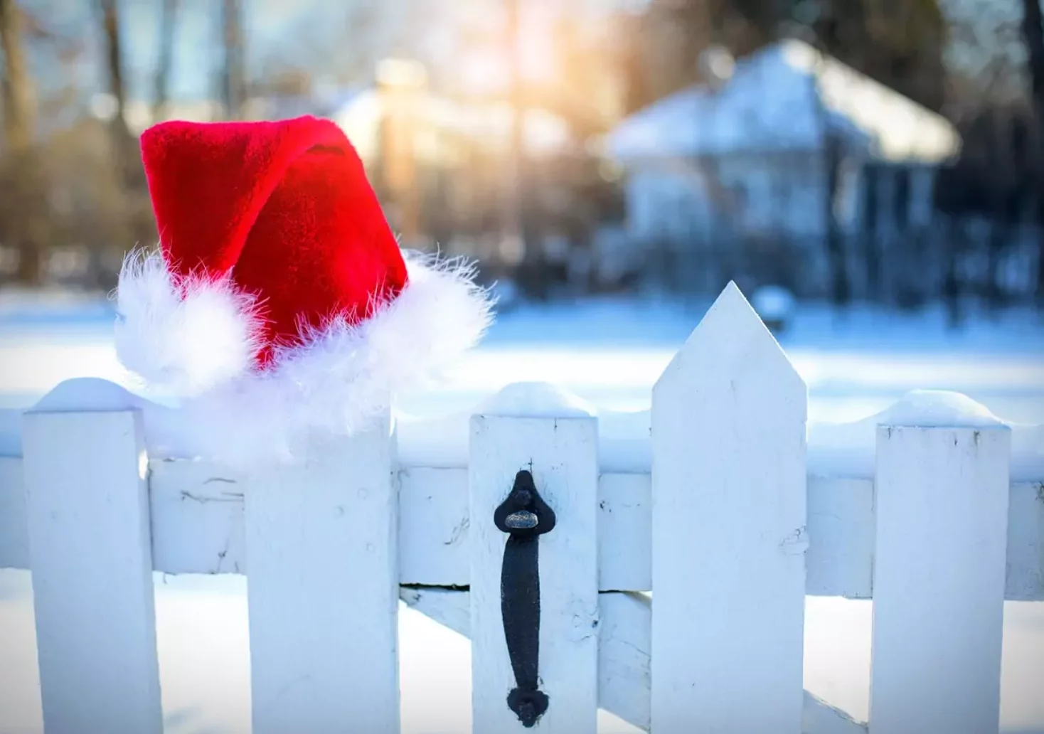 Foto in Beitrag von 5min.at: Zu sehen ist eine Weihnachtsmütze auf einem weißen Zaun. Dahinter liegt Schnee.