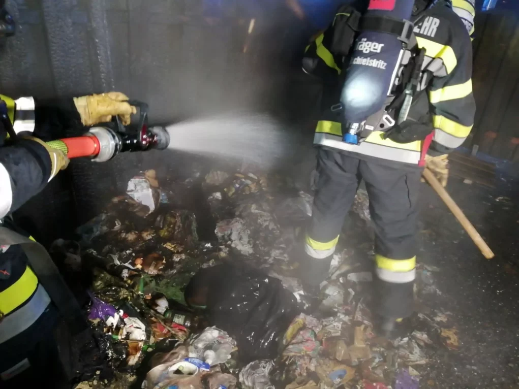 Müllinsel in Vollbrand: Feuerwehr mit schwerem Atemschutz im Einsatz
