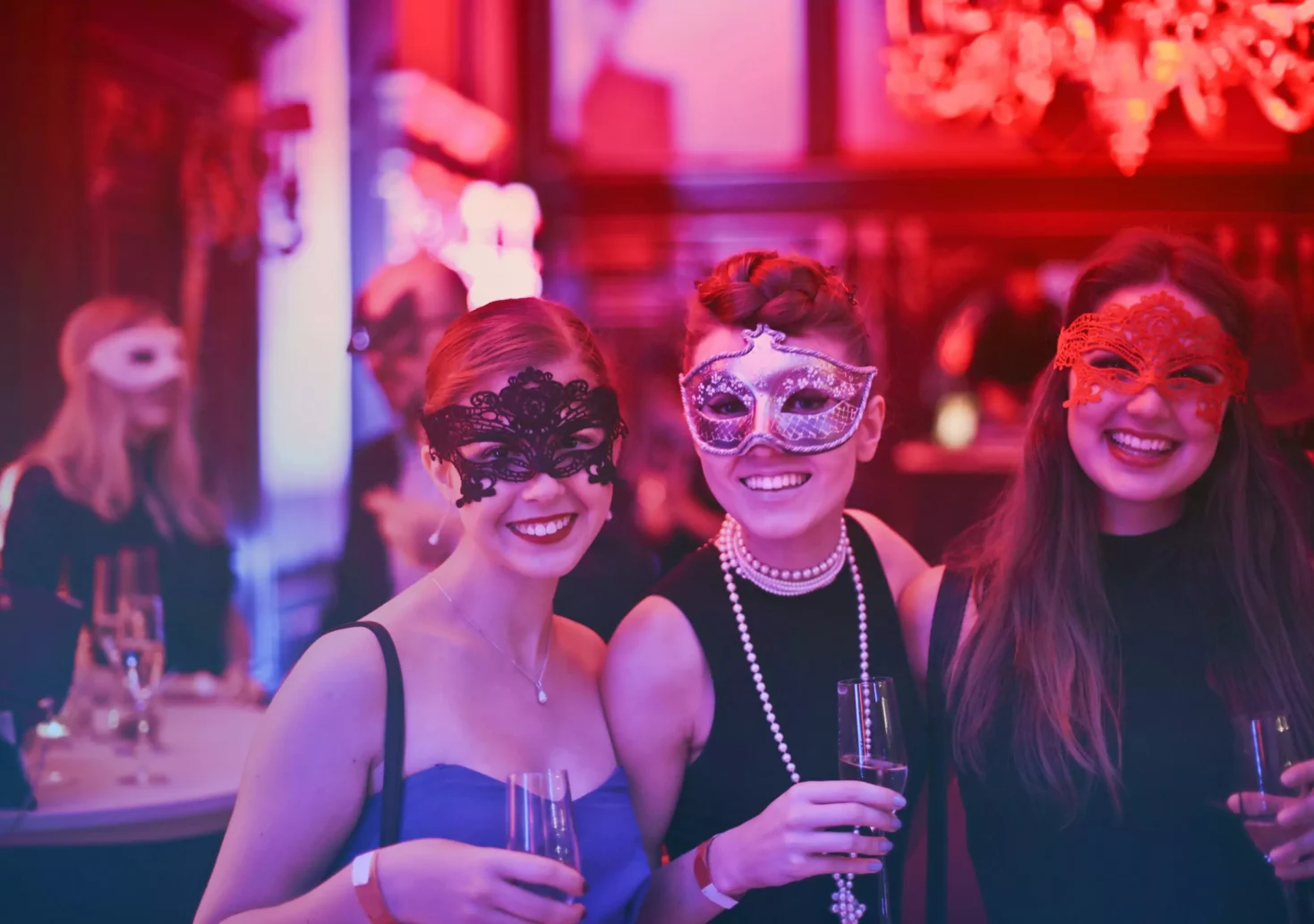Ein Bild auf 5min.at zeigt drei maskierte Frauen mit Getränken auf einer Veranstaltung.