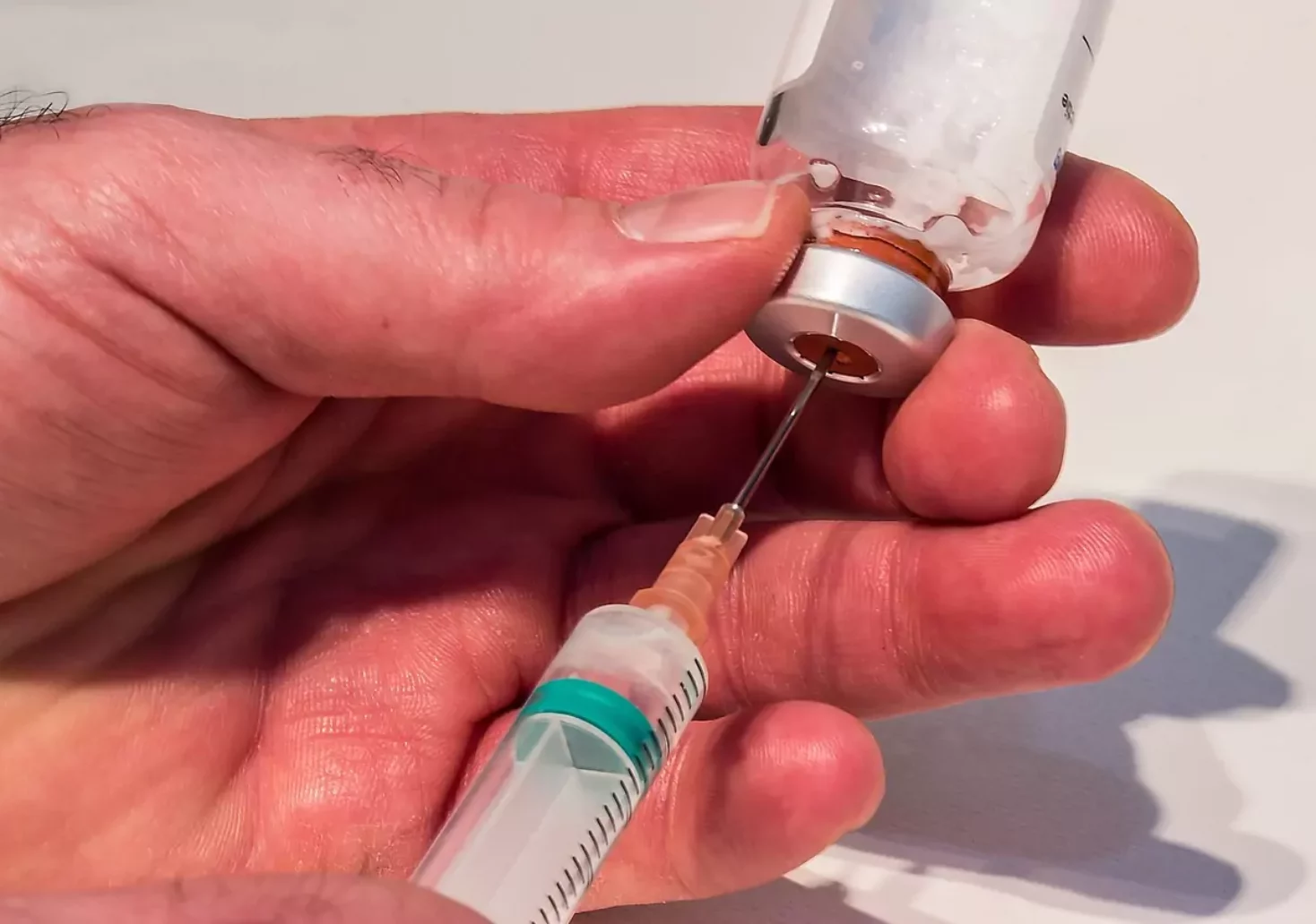 Ein Bild auf 5min.at zeigt, wie jemand einen Impfstoff mit einer Spritze aufnimmt.