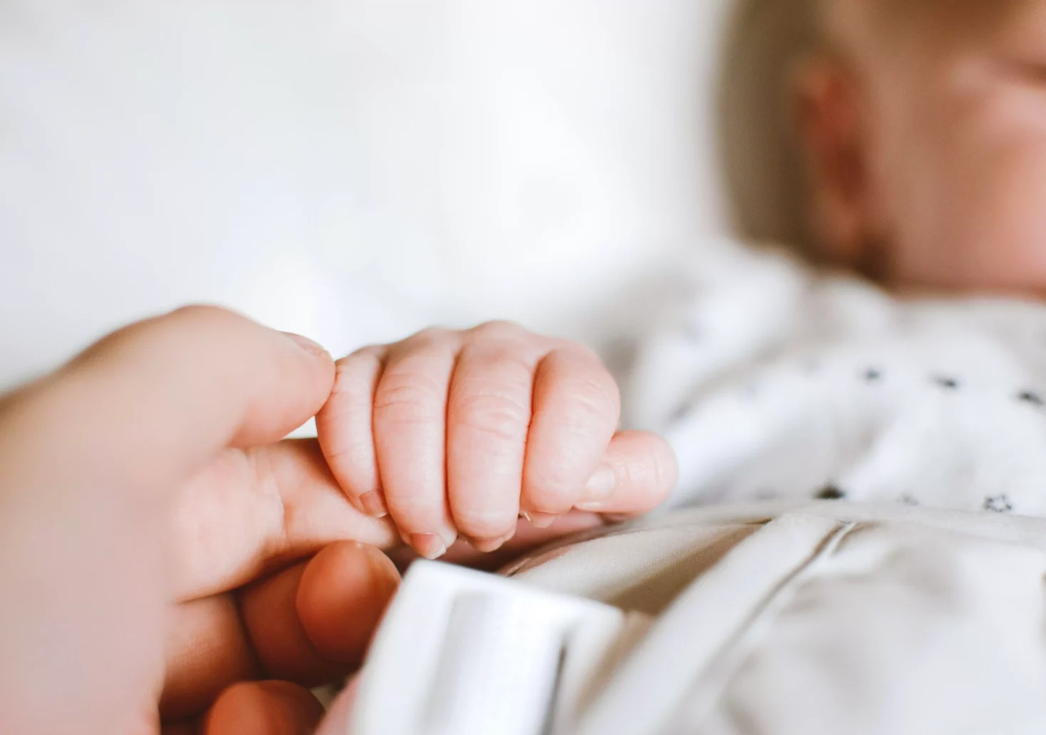 Ein Bild auf 5min.at zeigt ein Baby, dass den Finger eines Erwachsenen hält.