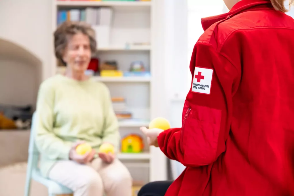 Bild auf 5min.at zeigt eine ältere Dame und eine Mitarbeiterin des Roten Kreuzes.