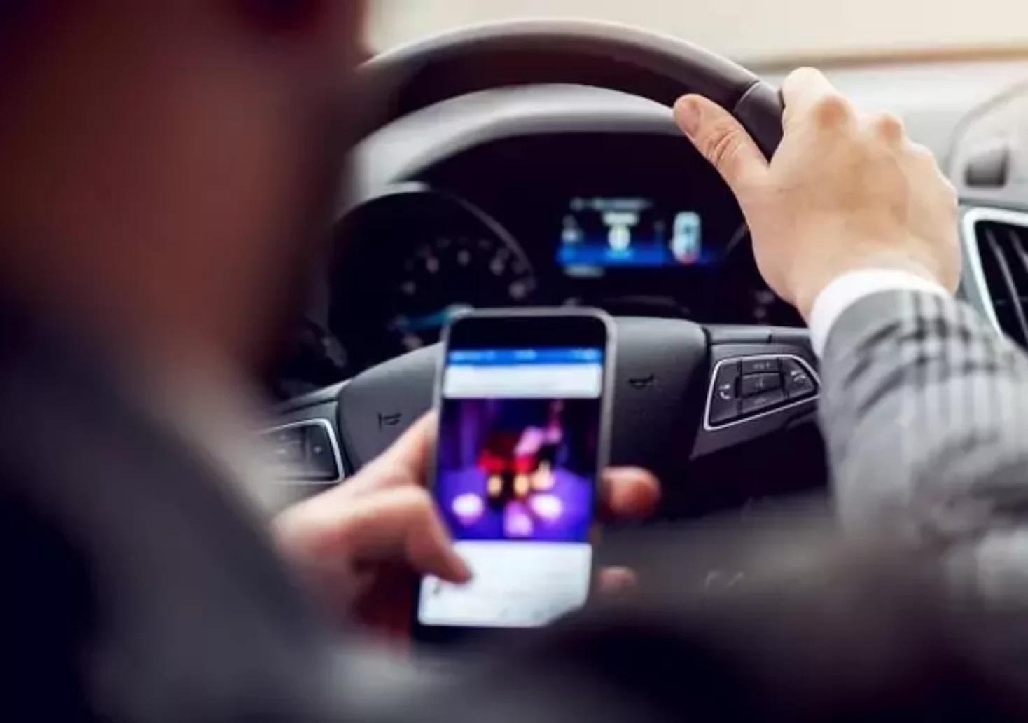Bild auf 5min.at zeigt einen Autofahrer mit dem Handy in der Hand.
