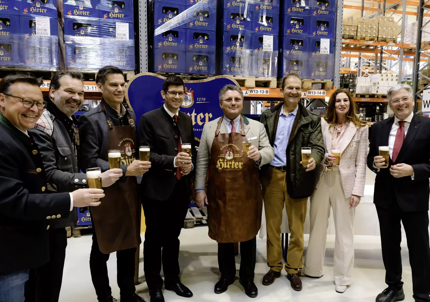 Das Bild auf 5min.at zeigt eine Gruppe von Menschen mit Bier bei der Eröffnung einer neuen Lagerhalle.