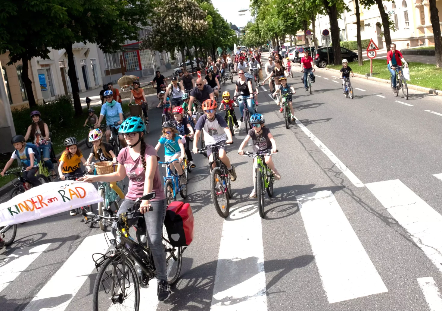 Ein Bild auf 5min.at zeigt Kinder und Erwachsene, die auf ihren Fahrrädern mitten auf einer Straße in Klagenfurt radeln.
