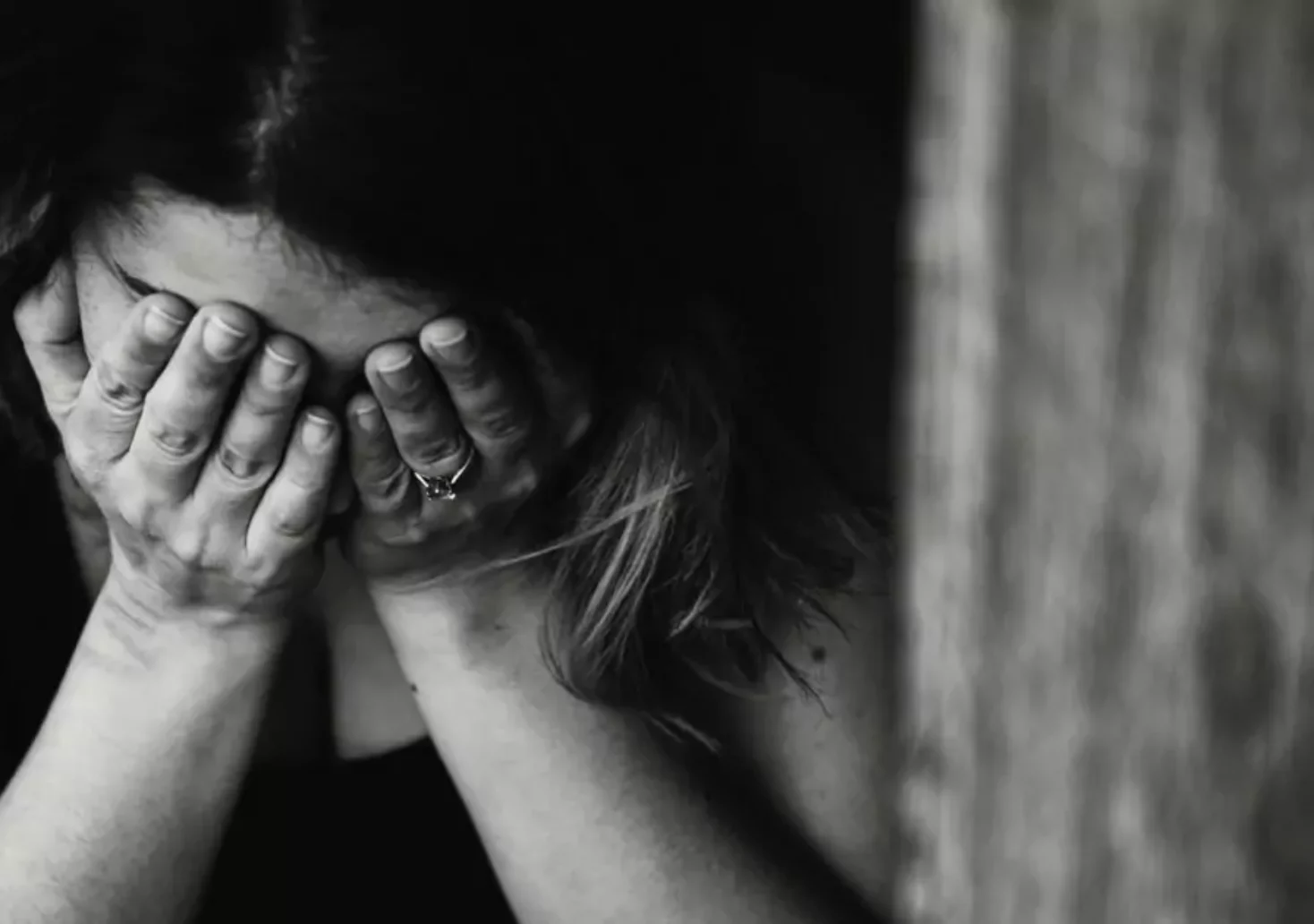 Foto in Beitrag von 5min.at: Zu sehen ist eine Frau, die ihre Hände vor dem Gesicht hat und scheinbar traurig ist. Die Szenerie ist in schwarz-weiß dargestellt.