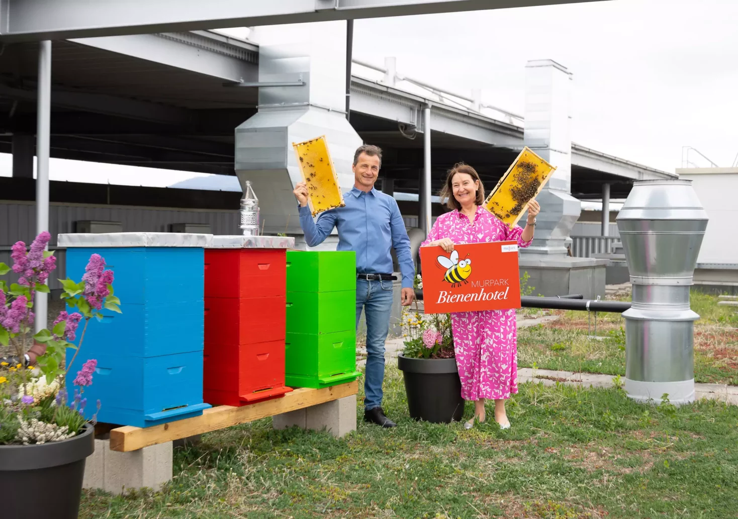 Bild auf 5min,at zeigt Imker Enver Kajtazovic und MURPARK Center-Managerin Edith Münzer vor den Bienenstöcken am Dach des MURPARK
