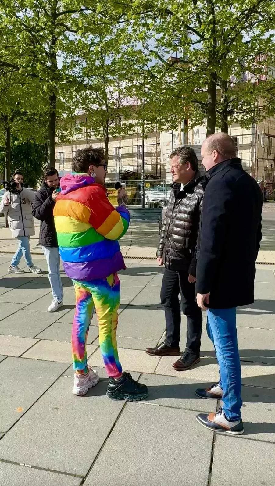 Foto in Beitrag von 5min.at: Zu sehen ist Ian Jules, wie er mit Bürgermeister Christian Scheider und Patrick Jonke spricht, im Hintergrund das Filmteam von RTL.