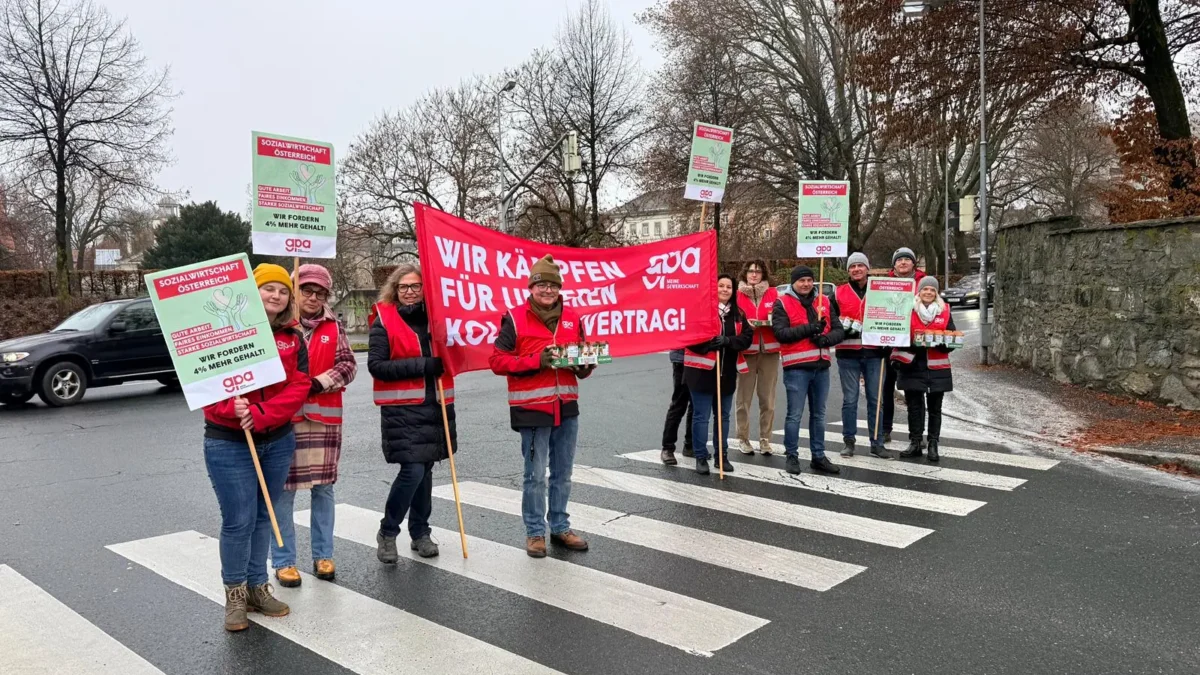 Ein Bild auf 5min.at zeigt, wie Demonstranten mit Plakaten an einer Kreuzung stehen.