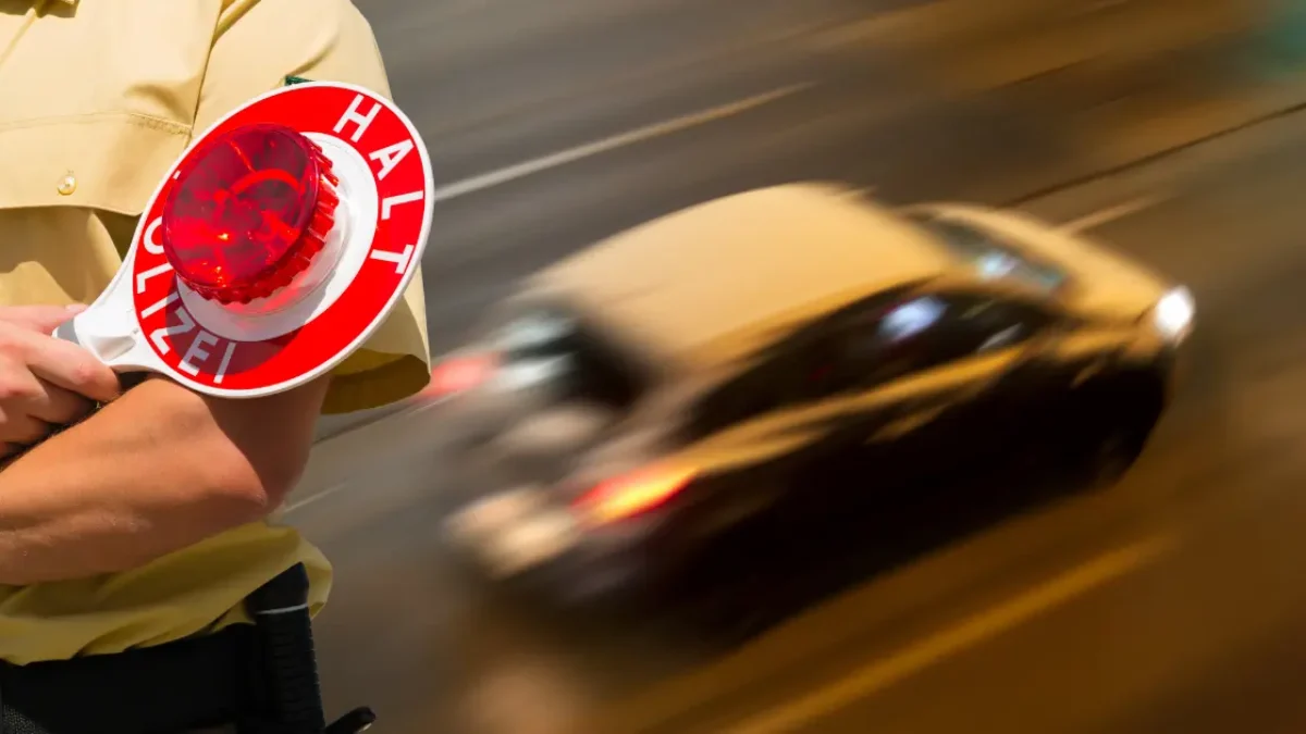 auf dem bild von 5min.at sieht man ein rasendes auto bei einer polizeikontrolle.